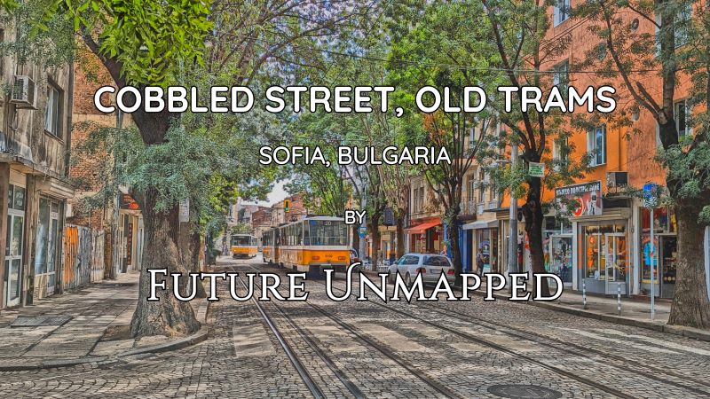 Dry, cobblestone street with integrated tracks - bordered by tall trees and graffitied buildings in family-friendly urban space - vibrates from braking tram.