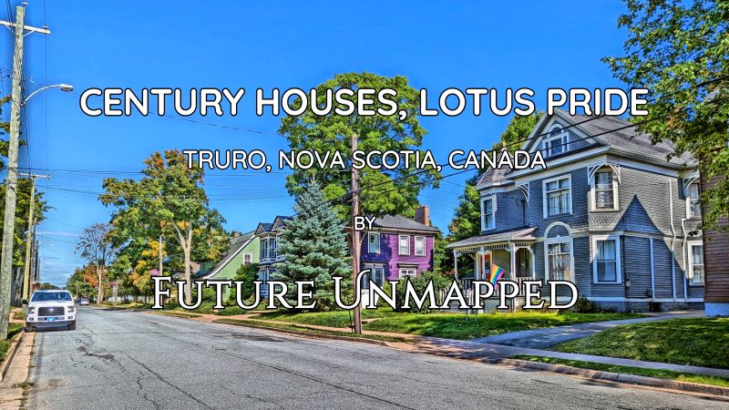 Quiet, tree-lined residential street - among distinctly-coloured, older homes with unique architecture - includes rainbow flag on porch of women's resource centre.