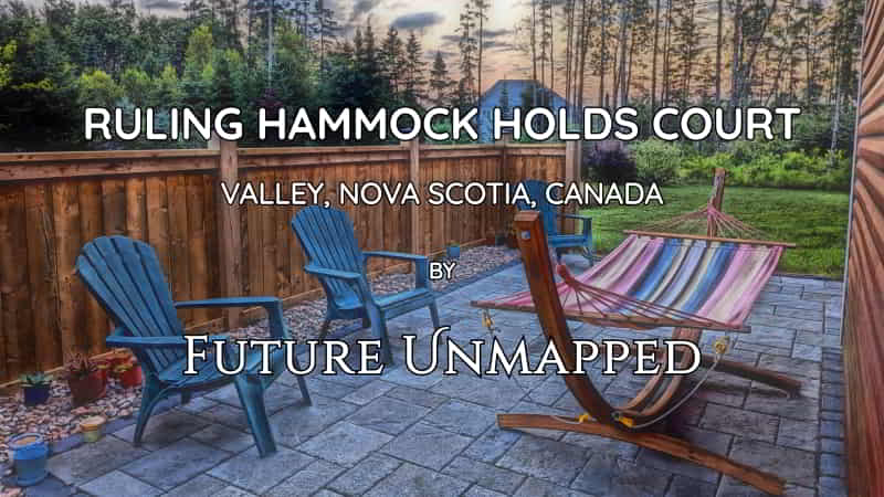 Wood-framed, freestanding hammock dominates neatly-paved, stone-interlocked patio area - in quiet suburban sideyard - with adirondack chairs backing onto wooden fence.