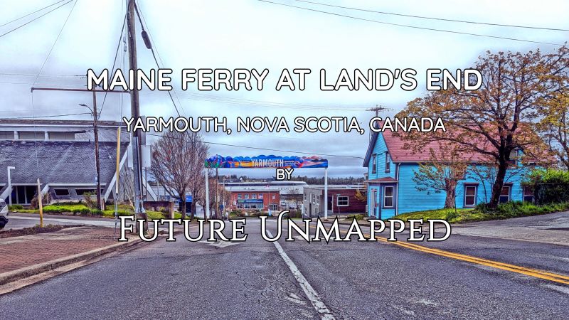 Canada/US ferry and terminal building framed by colourful port town signage - during foggy, early-Spring morning - on quiet street flanked by old visitor centre and vibrant property.